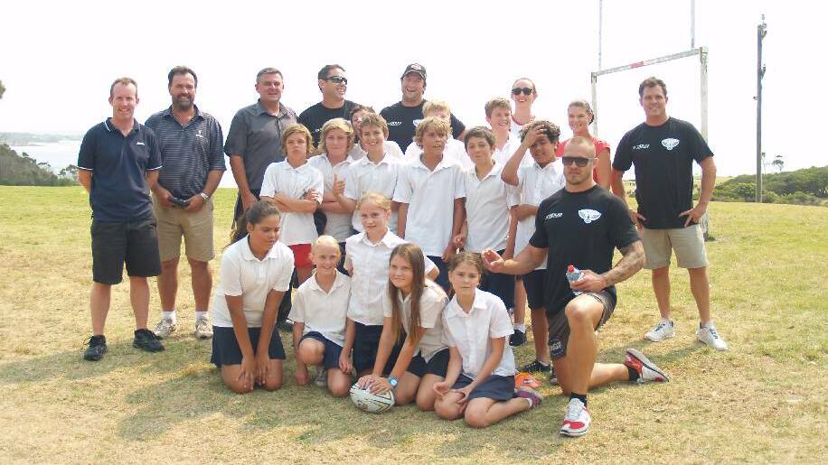 LEAGUE LEGENDS: Mr George, Mr Russack, principal Sweeney, Brad “Freddy” Fittler, Nathan Hindmarsh, Miss Harding, Mrs Hextell and Matt Cooper with the Year Six students at Narooma Public School on Monday after an action-packed game on the field which was part of the Hogs for Homeless journey around NSW to raise funds for homeless youths.