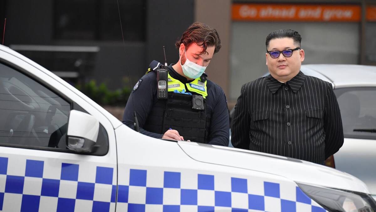 A man dressed as North Korean leader Kim Jong-un is spoken to by Victoria Police after crashing the Prime Minister's press event. Picture: AAP