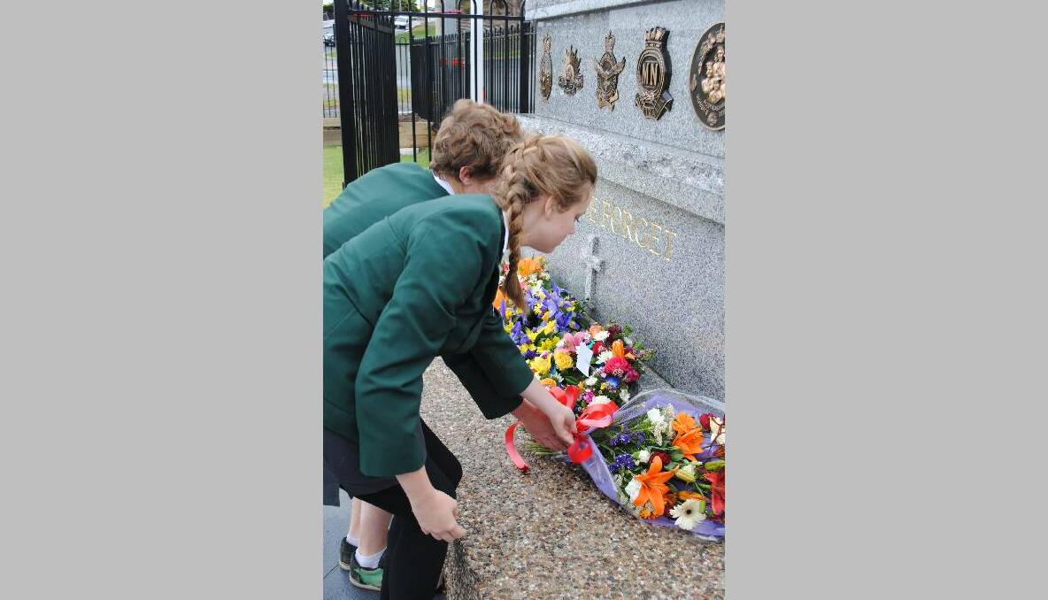 RESPECT: Narooma High School students Ashleigh Abill and Daniel Alderton place a bouquet of flowers at the memorial at Club Narooma on Remembrance Day. 