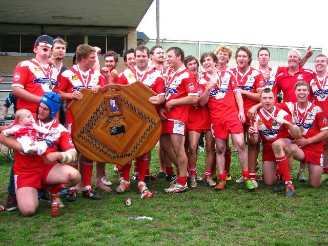 GRAND FINAL WINNERS: The ecstatic Narooma Devils following their win against the Moruya Sharks 20 to 14. Pictured are Gene Willis with his baby daughter, Ricky Falconer, Stephen Brown, Kane Ayers, Tod Wright (obscured), Simon Hodge, Callum Annand, Troy Beecham, Kyle Debreceny, Tyler Hextell, Tom Cooney, Luke Pryor, Josh Schymageour, Pat Willis, Tim Keegan, Kyle Burnell, Jamie Wright Devils president, Justin Keegan and Blake Robinson. 